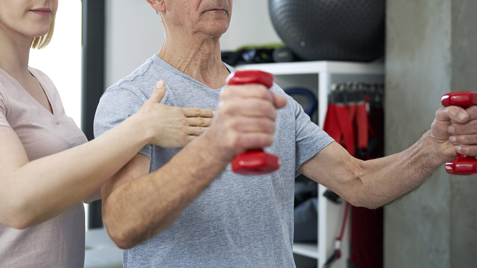 Female physical therapist conducts dumbbell training